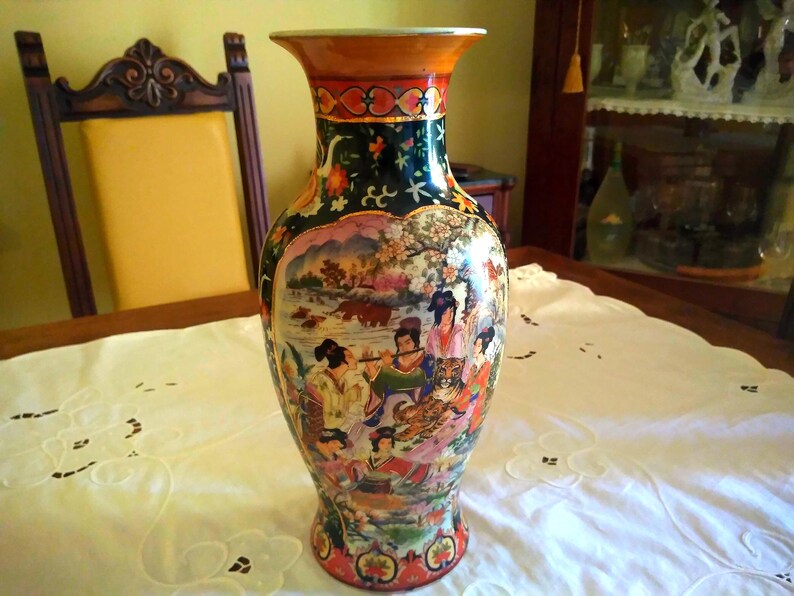Pu&ograve; includere: Un vaso decorativo in ceramica con bocca larga e base svasata. Il vaso presenta una scena dipinta dettagliata con figure, animali e paesaggi dai colori vivaci. Il bordo &egrave; arancione e il corpo &egrave; verde scuro.