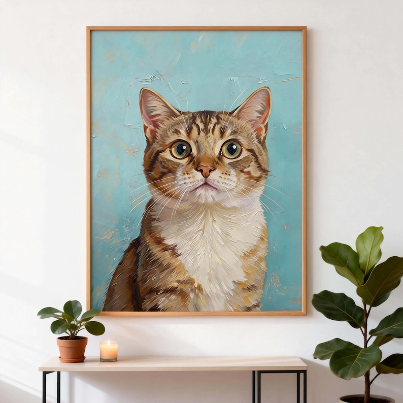 May include: A framed cat portrait. The artwork features a tabby cat with brown and tan fur, set against a textured light blue background. The cat has large, expressive eyes and is framed in a light wood.