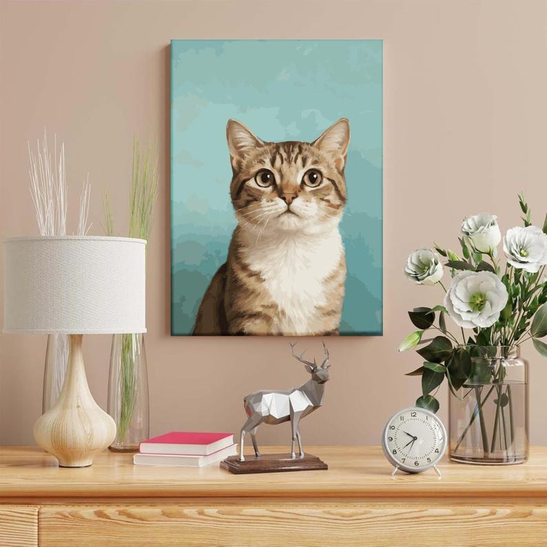 May include: A canvas print of a tabby cat with brown and white fur, set against a teal background. The cat has large, expressive eyes and is the focal point of the artwork. The print is displayed on a wall above a wooden table.