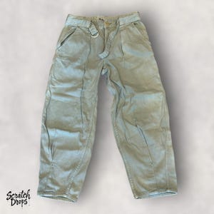 Puede incluir: Pantalones de pierna ancha verde claro con cinturón a juego y hebilla plateada. Los pantalones tienen bolsillos delanteros y cintura alta. La tela parece ser un denim ligero o similar. Los pantalones se muestran sobre un fondo blanco.