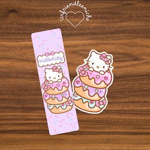 May include: A bookmark and sticker featuring Hello Kitty. The bookmark is lavender with a repeating pattern of sprinkles and the words "Hello Kitty". The sticker and bookmark both feature Hello Kitty sitting on a stack of three donuts with pink frosting and bows.