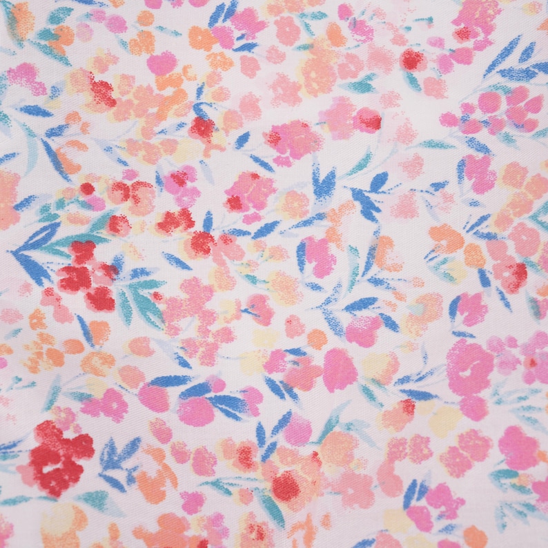 Puede incluir: Una tela blanca con un estampado floral de peque&ntilde;a escala. Las flores son en tonos de rosa, rojo, naranja y amarillo. El fondo es blanco.