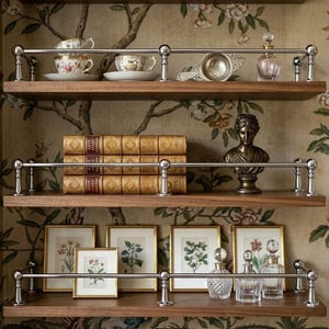 May include: A display of wooden shelves with various decorative items. The top shelf has teacups, a tea strainer, and a perfume bottle. The middle shelf holds antique books and a bronze bust. The bottom shelf displays framed botanical prints and glass perfume bottles.