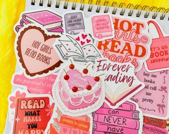 Op de afbeelding: Een verzameling roze en rode stickers met een boekthema met verschillende spreuken, waaronder "Hot Girls Read Books", "Forever Reading", "Read What Makes You Happy" en "Can Never Have Too Many".
