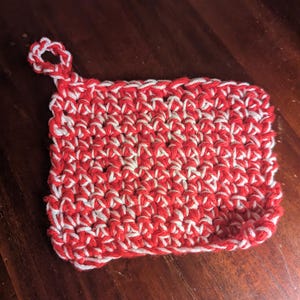 May include: Red and white crocheted dishcloth with a loop handle.