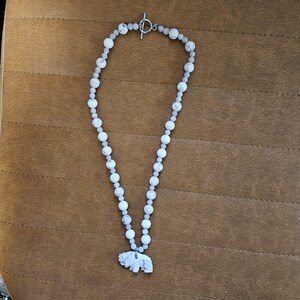 May include: A white and grey beaded necklace with a white stone elephant pendant.