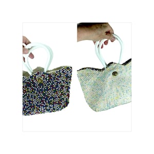 Puede incluir: Dos pequeños bolsos de mano con cuentas y asas blancas. Una bolsa es azul marino con puntos de colores, la otra es de tweed claro. Ambas bolsas tienen un cierre de botón dorado.