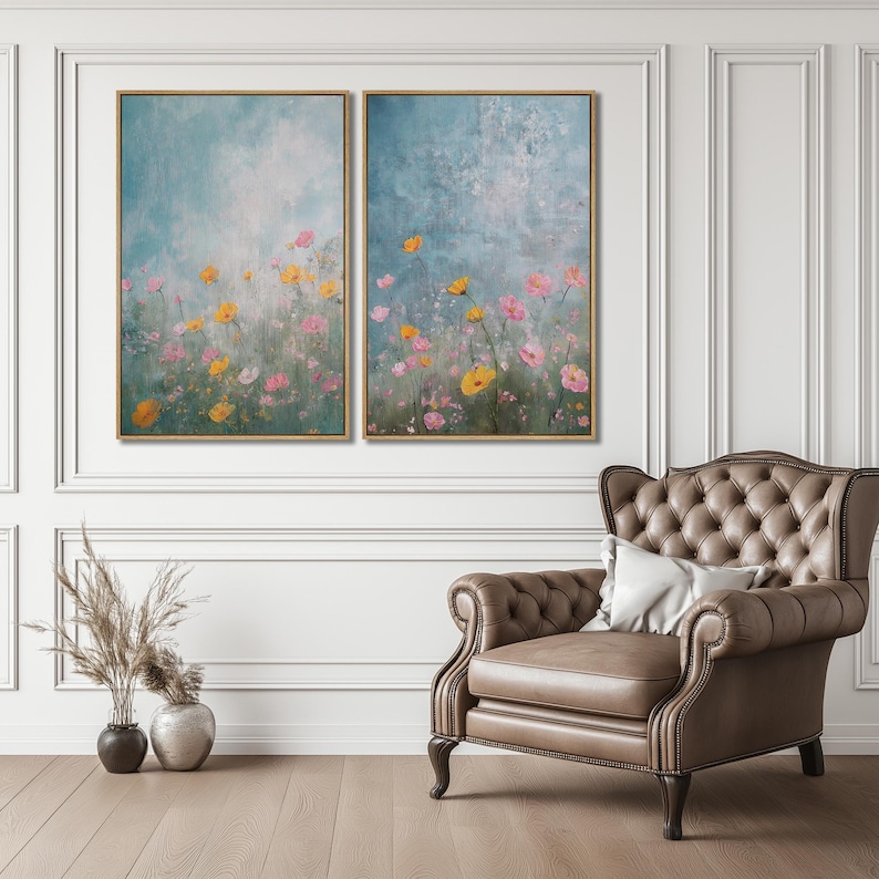 K&ouml;nnte beinhalten: Zwei gerahmte Bilder mit einem Feld aus rosa und gelben Blumen vor einem blauen und wei&szlig;en Hintergrund. Die Bilder h&auml;ngen an einer wei&szlig;en Wand &uuml;ber einem braunen Ledersessel.