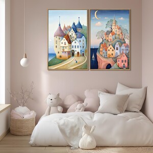 May include: Two framed watercolor paintings depict whimsical European villages. One shows a coastal town with colorful buildings and a road. The other features a village on a cliff with a sailboat in the sea and a crescent moon in the sky.