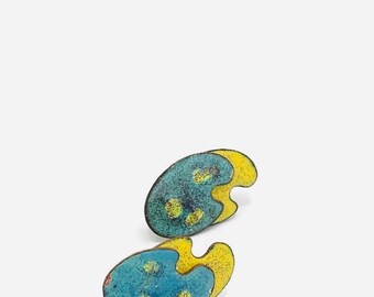 May include: A pair of blue and yellow enamel earrings shaped like abstract paint palettes. The earrings have a speckled texture and yellow accents.