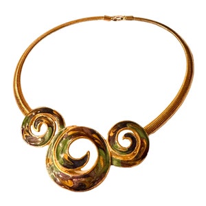 May include: A gold chain necklace with a green, gold, and purple swirl design pendant.