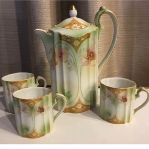 May include: A vintage tea set with a green and gold floral design. The set includes a teapot and four cups.