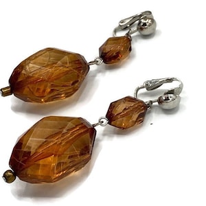 May include: A pair of amber glass clip-on earrings with three faceted beads on each earring.