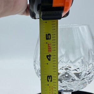 May include: A clear glass goblet with a cut crystal design. The goblet is 5 inches tall and is being measured with a tape measure.