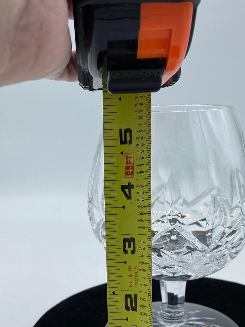 May include: A clear glass goblet with a cut crystal design. The goblet is 5 inches tall and is being measured with a tape measure.