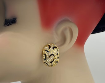 May include: Gold tone clip-on earrings with black enamel and clear rhinestones in a floral design.