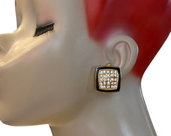 May include: A pair of gold tone clip-on earrings with a black enamel square setting and clear rhinestones.