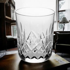 Puede incluir: Un vaso transparente de cristal tallado. El vaso est&aacute; sobre una superficie de madera.