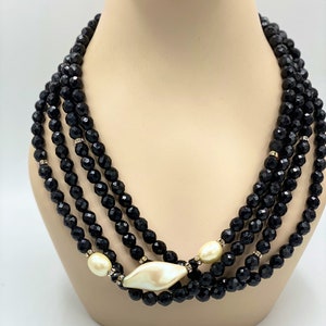 Pu&ograve; includere: Una collana multifilo di perle nere con un grande ciondolo bianco avorio sfaccettato. La collana &egrave; realizzata con perle nere sfaccettate e ha un accento di perla.