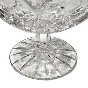 May include: A clear glass bowl with a cut crystal design and a wide, flat base. The bowl is on a white background.