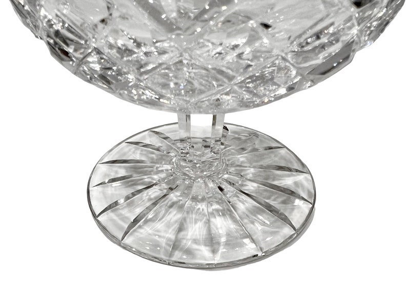 May include: A clear glass bowl with a cut crystal design and a wide, flat base. The bowl is on a white background.