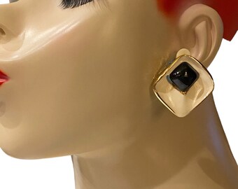 May include: A pair of gold tone clip-on earrings with a white and black geometric design. The earrings have a square shape with a black center and a white border.