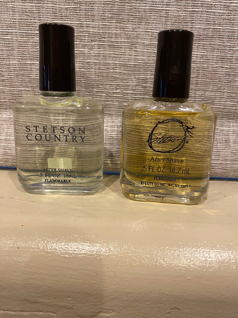 Pode incluir: Duas garrafas de vidro transparente de aftershave. A garrafa &agrave; esquerda est&aacute; etiquetada "Stetson Country After Shave 5 fl oz 15 ml Flammable". A garrafa &agrave; direita est&aacute; etiquetada "Stetson After Shave 0.5 fl oz 14.7 ml Flammable Coty US Inc., NY, NY 10017".