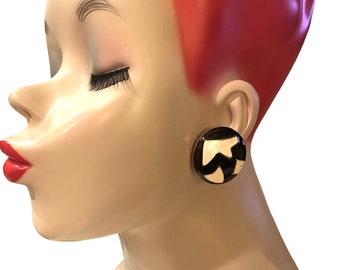 May include: A pair of black and white round clip-on earrings with a geometric design.