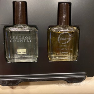 Pode incluir: Duas pequenas garrafas de vidro de aftershave em uma caixa preta. A garrafa &agrave; esquerda est&aacute; etiquetada como "Stetson Country" e a garrafa &agrave; direita est&aacute; etiquetada como "After Shave 0.5 fl oz 14.7 ml".