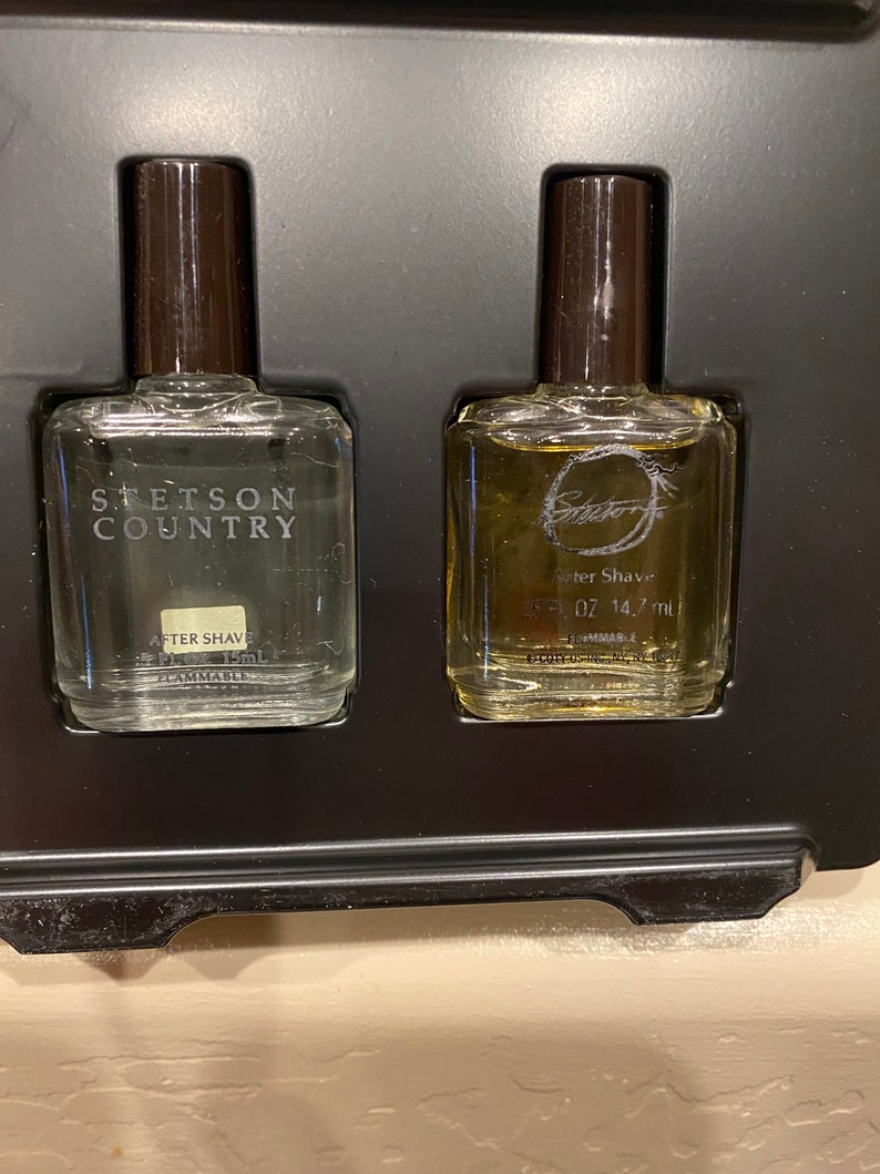 Pode incluir: Duas pequenas garrafas de vidro de aftershave em uma caixa preta. A garrafa &agrave; esquerda est&aacute; etiquetada como "Stetson Country" e a garrafa &agrave; direita est&aacute; etiquetada como "After Shave 0.5 fl oz 14.7 ml".