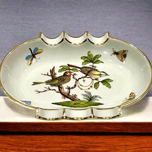 Puede incluir: Plato ovalado de porcelana blanca con borde dorado y borde festoneado. El plato presenta un diseño pintado a mano de dos pájaros posados en una rama con hojas verdes y mariposas.