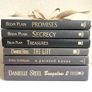 May include: A stack of eight black and gray hardcover books with gold lettering. The titles of the books are "Promises", "Secrecy", "Treasures", "The Gift", "a painted house", and "Bungalow 2".