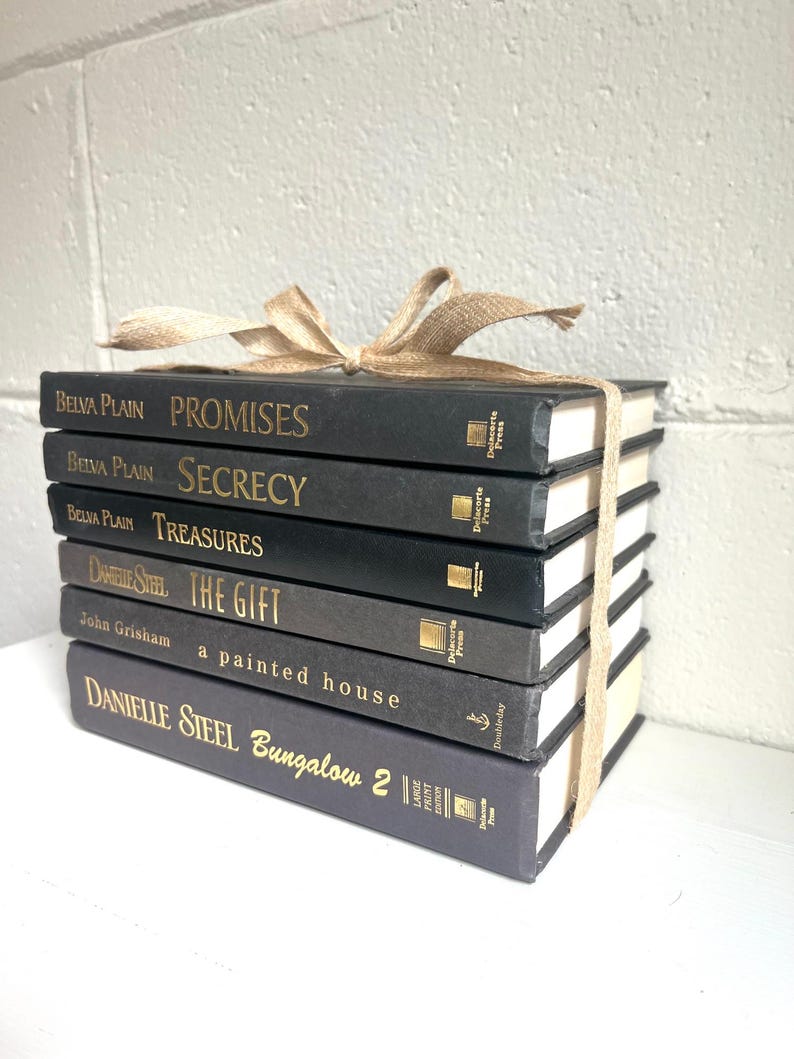 May include: A stack of eight black hardcover books with gold lettering on the spines. The books are tied together with a brown ribbon. The titles of the books are "Promises", "Secrecy", "Treasures", "The Gift", "A Painted House", and "Bungalow 2".