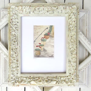 May include: A framed watercolor painting of a set of stairs with potted plants and red flowers. The frame is white with ornate detailing.
