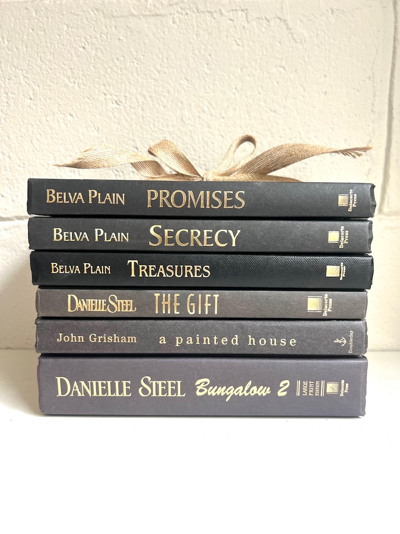 May include: A stack of eight black and gray hardcover books with gold lettering. The titles of the books are "Promises", "Secrecy", "Treasures", "The Gift", "a painted house", and "Bungalow 2".