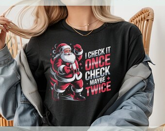 May include: Dark gray t-shirt featuring a cartoon Santa Claus in a red suit with the text "I CHECK IT ONCE CHECK MAYBE TWICE". The shirt is a festive holiday design.