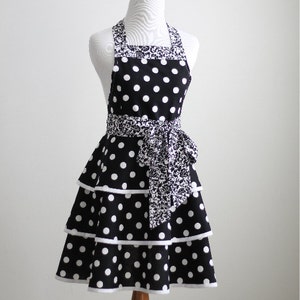 May include: A black and white polka dot apron with a tiered skirt and a patterned waistband and neck strap. The apron is displayed on a mannequin. The text "PDF Sewing Pattern" is at the bottom.
