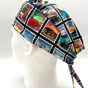 May include: A black scrub hat with a colorful print of national park stamps. The hat has a tie at the back.