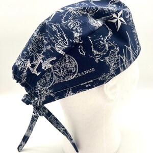 May include: A blue surgical scrub hat with a white world map and nautical design. The hat has a white star and the text "OCEANUS" on it.
