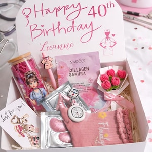 Op de afbeelding: Een cadeauverpakking met roze items: glazen beker, pen, gezichtsmasker, zakhorloge, sokken en een boeket. Op het deksel staat "Happy 40th Birthday Leeanne" in roze.