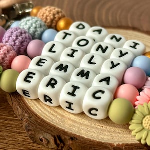 May include: A colorful silicone bead necklace with white letter beads spelling out the names "Danny", "Tony", "Lily", "Emma", and "Eric".