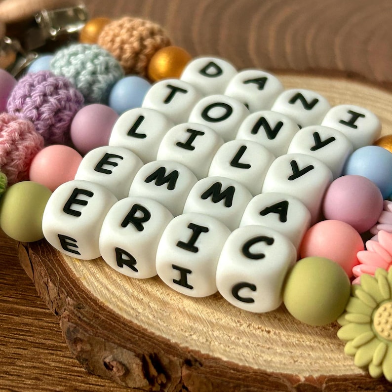May include: A colorful silicone bead necklace with white letter beads spelling out the names "Danny", "Tony", "Lily", "Emma", and "Eric".