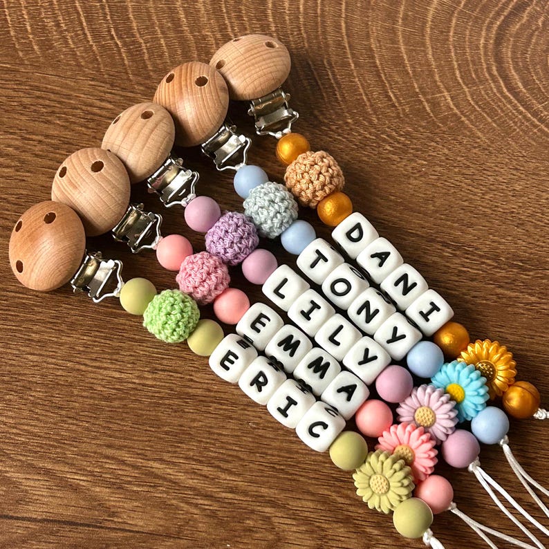May include: Five wooden teethers with clips and colorful beads, including crocheted beads, and letter beads spelling out the names Dani, Tony, Lily, Emma, and Eric.