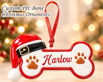 May include: A bone-shaped Christmas ornament featuring a red Santa hat with a black belt and gold buckle. The white ornament has two brown paw prints and the name Harlow in red script. A red ribbon loop is attached for hanging the decoration.