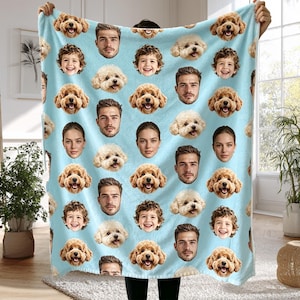 May include: A light blue fleece blanket featuring a repeating pattern of various human faces and golden-brown dog faces. The design includes portraits of men, women, and children interspersed with smiling dogs, creating a personalized photo collage layout.