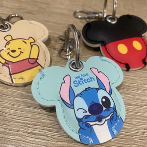 May include: A selection of Disney character keyrings. One features Winnie the Pooh, another Mickey Mouse, and a third, Stitch. The Stitch keyring is light blue and has the text "we love Stitch". The Mickey Mouse keyring is black and red.