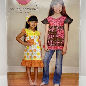 Pode incluir: Um pacote de padrões de costura com duas meninas a modelar vestidos e camisas estilo túnica Frida. O pacote inclui padrões para tamanhos 2T-10, com um lenço de cabeça. A marca Modkid é visível, com o texto "sewing patterns by Patty Young."