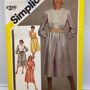 Puede incluir: Patrón de costura Simplicity para un vestido de talla 10 Miss. El patrón presenta a una mujer con un vestido a rayas con cinturón. El sobre del patrón es amarillo y blanco con el logotipo de Simplicity.