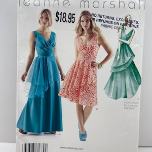 May include: A Simplicity sewing pattern envelope 1689 for Leanne Marshall dresses. The front shows two dress variations: a floor-length teal gown and a knee-length orange and white patterned dress, with illustrations and text including size info.