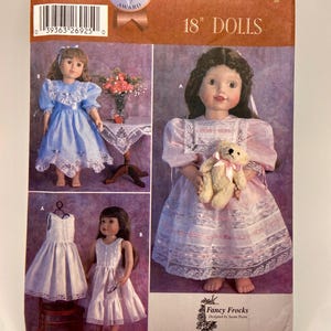 May include: Simplicity sewing pattern for 45.7 cm dolls. The pattern features three doll dresses in different styles. The cover includes the text "5428", "ONE SIZE", "HEIRLOOM Dolls 2001 AWARD", "Simplicity", "18" DOLLS", and "Fancy Frocks".